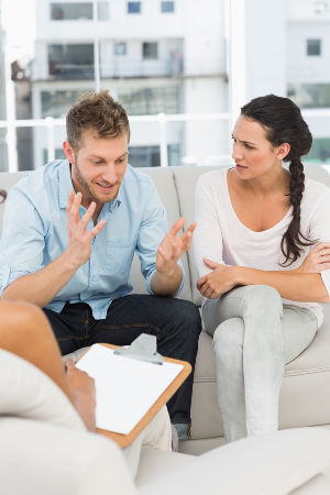 Unhappy man talking at couples therapy session in therapists office